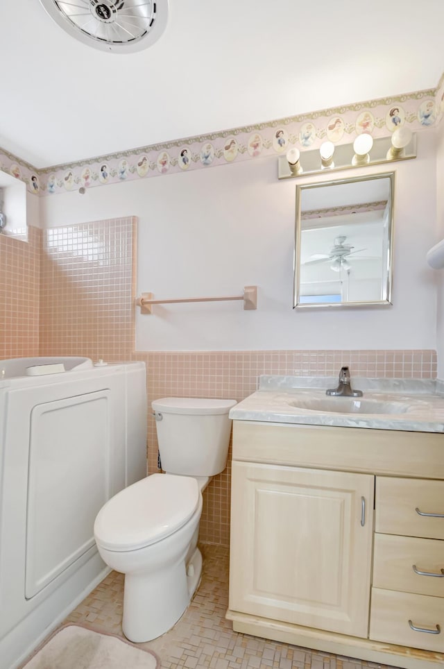 bathroom with toilet, tile patterned flooring, tile walls, and vanity