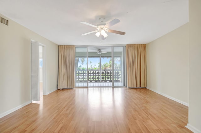 spare room featuring light wood-type flooring, expansive windows, and ceiling fan