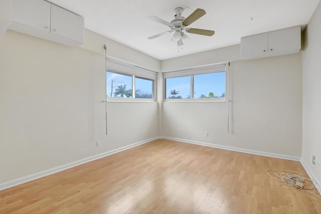 empty room with ceiling fan, a wall mounted air conditioner, and light hardwood / wood-style floors