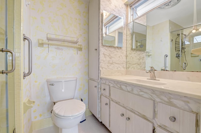 bathroom featuring toilet, vanity, and a shower with shower door