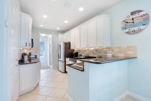 kitchen featuring light tile patterned floors, a peninsula, tasteful backsplash, and white cabinetry