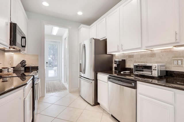 kitchen featuring a toaster, stainless steel appliances, decorative backsplash, white cabinets, and dark stone counters