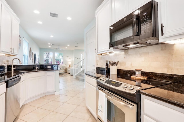 kitchen with light tile patterned floors, stainless steel appliances, visible vents, white cabinetry, and dark stone counters