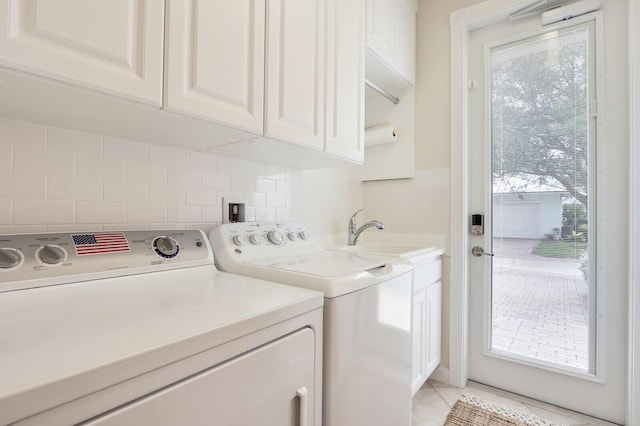 clothes washing area with cabinet space, light tile patterned floors, a sink, and washing machine and clothes dryer