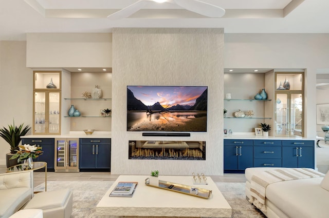 living room with wine cooler, a large fireplace, a raised ceiling, and a dry bar