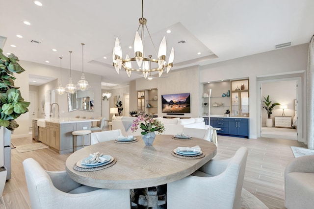 dining space featuring a tray ceiling, visible vents, and an inviting chandelier