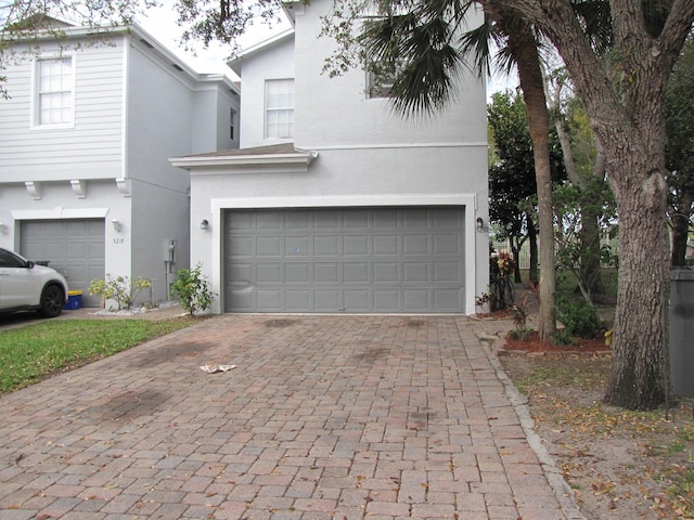 view of front facade with stucco siding, decorative driveway, and a garage