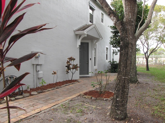 property entrance with stucco siding and fence
