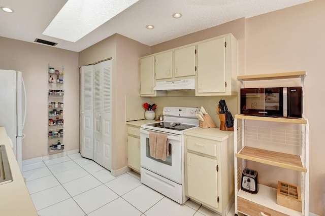 kitchen featuring light tile patterned floors, white appliances, and cream cabinets