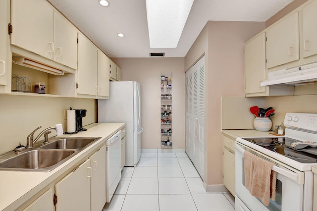 kitchen with white appliances, light tile patterned floors, sink, and cream cabinetry