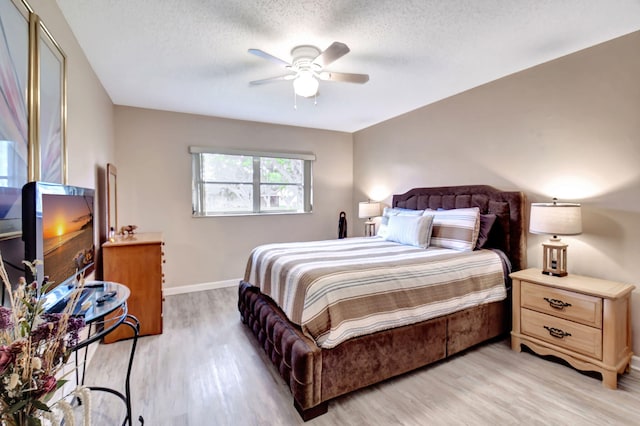 bedroom with light wood-type flooring, ceiling fan, and a textured ceiling