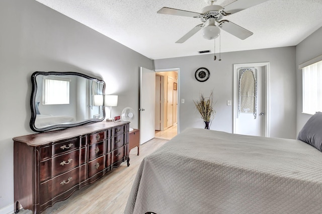 bedroom with light wood-type flooring, multiple windows, and a textured ceiling