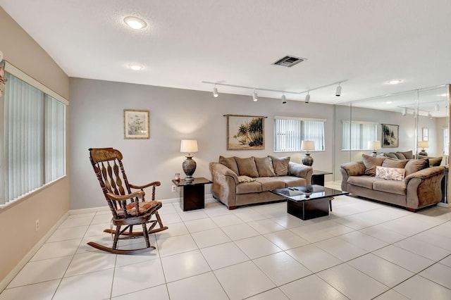 living room featuring a textured ceiling, track lighting, and light tile patterned floors