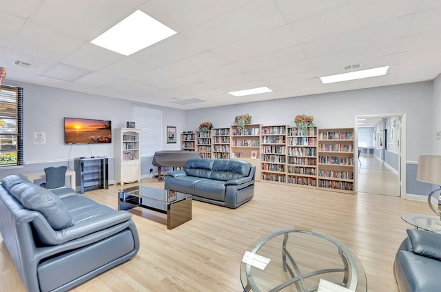 living room with light hardwood / wood-style floors and a drop ceiling