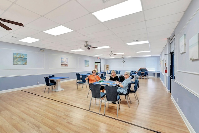 dining area with light wood-type flooring, ceiling fan, and a drop ceiling