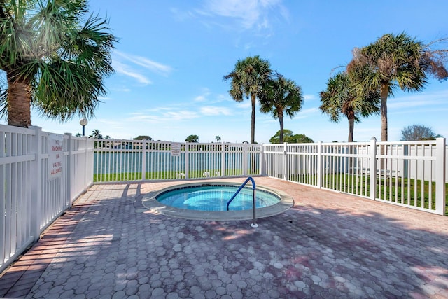 view of pool featuring a patio, a water view, and a hot tub