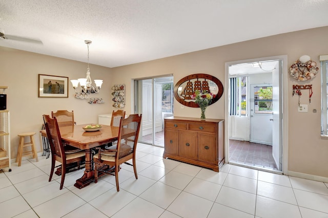 tiled dining room with a textured ceiling and a chandelier