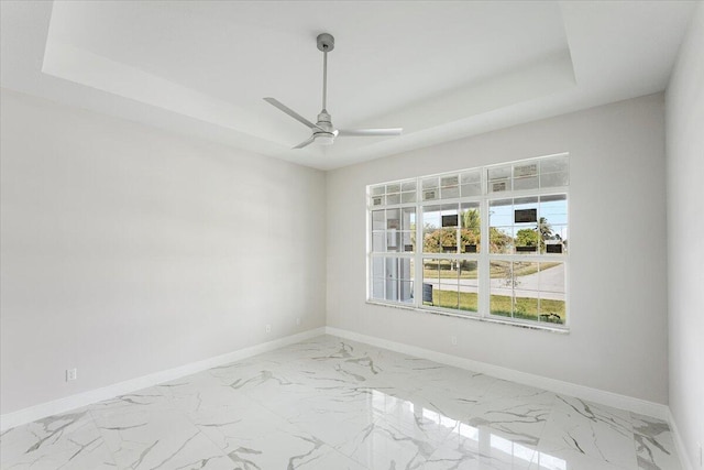 empty room featuring a raised ceiling and ceiling fan