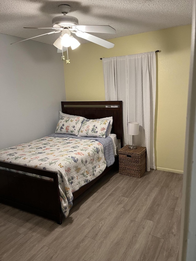 bedroom with a textured ceiling, hardwood / wood-style floors, and ceiling fan