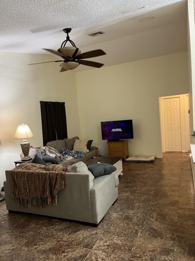 living room featuring ceiling fan and a textured ceiling