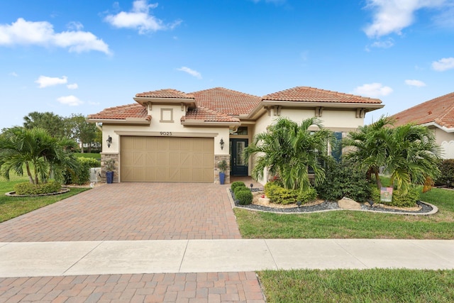 mediterranean / spanish house with an attached garage, stone siding, decorative driveway, and stucco siding