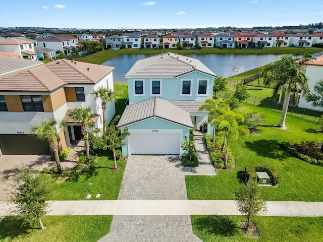 view of front of home with decorative driveway, a water view, fence, a garage, and a residential view