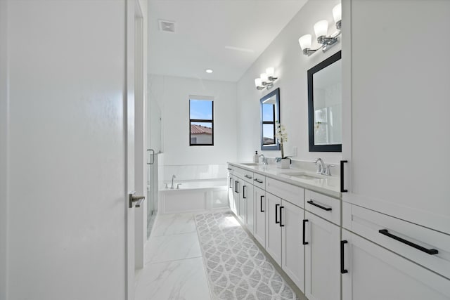 full bath featuring a garden tub, marble finish floor, a sink, and visible vents