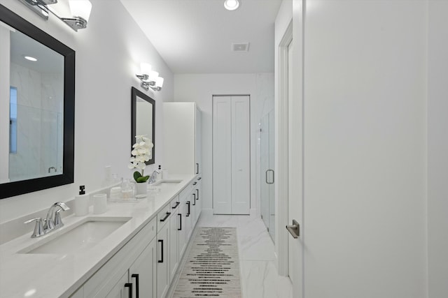 full bath with a sink, marble finish floor, double vanity, and a closet