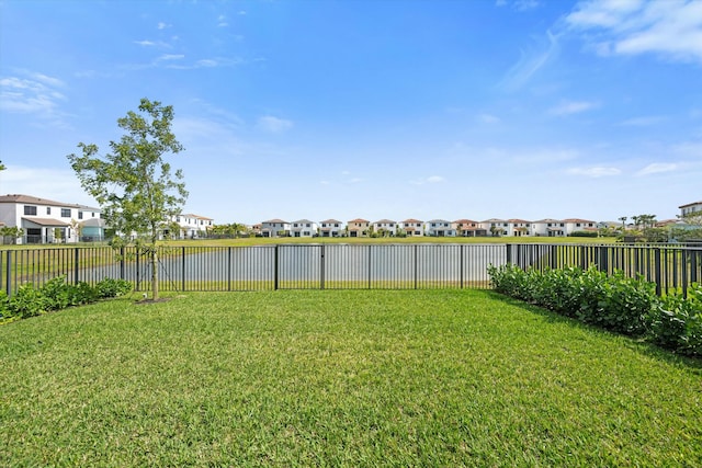 view of yard featuring a water view, a fenced backyard, and a residential view