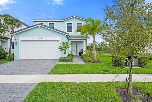 traditional-style house with an attached garage, stucco siding, decorative driveway, and a front yard