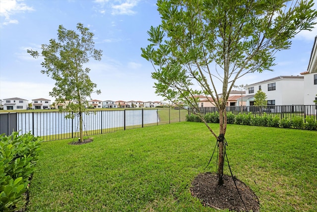 view of yard featuring a water view, a fenced backyard, and a residential view