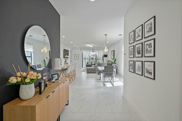 hall featuring marble finish floor, recessed lighting, plenty of natural light, and baseboards