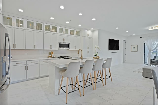 kitchen with stainless steel appliances, open floor plan, light countertops, and glass insert cabinets