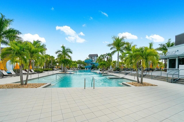 community pool with a water slide and a patio