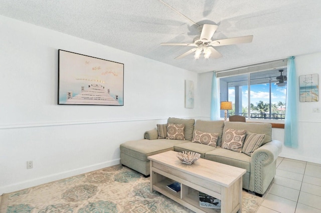 living room with a textured ceiling, ceiling fan, light tile patterned floors, and baseboards