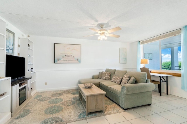 living room with light tile patterned floors, ceiling fan, baseboards, and a textured ceiling