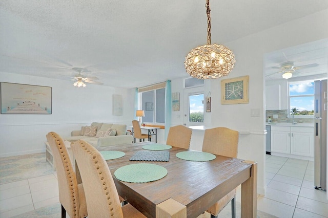 dining space with a healthy amount of sunlight, ceiling fan with notable chandelier, and light tile patterned flooring