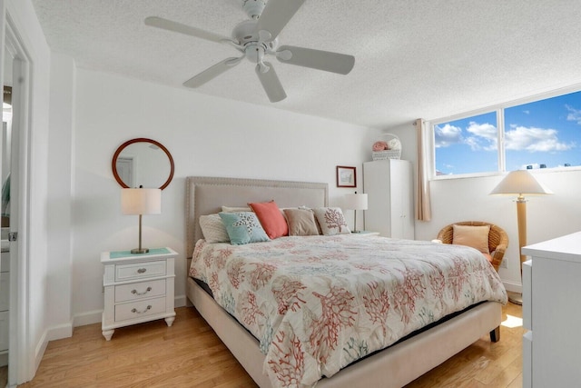 bedroom with light wood-type flooring, ceiling fan, a textured ceiling, and baseboards