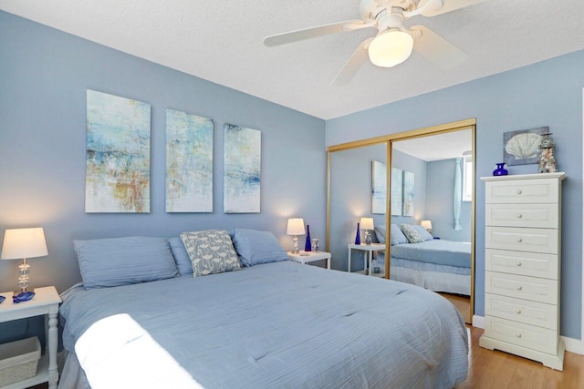 bedroom with ceiling fan, a closet, and light wood-style flooring