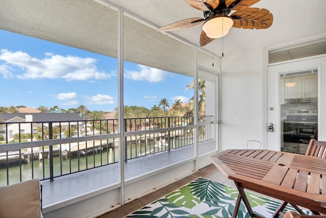 sunroom / solarium with a water view and ceiling fan