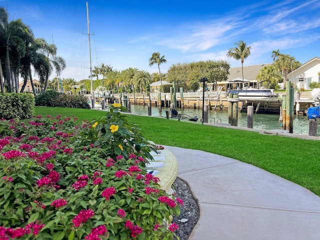 view of home's community with a dock, a water view, boat lift, and a lawn