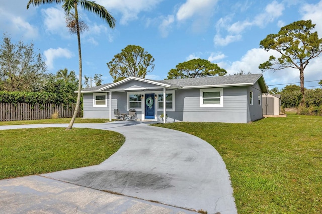 single story home featuring concrete driveway, an outdoor structure, a front lawn, and a storage unit