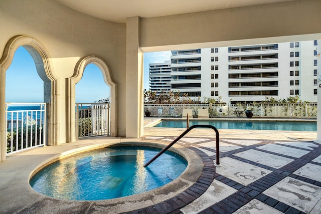 community pool featuring a patio, a community hot tub, and fence