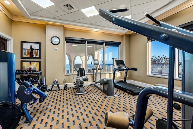 workout area featuring baseboards, crown molding, and a paneled ceiling