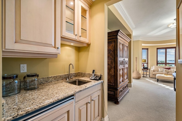 kitchen featuring a sink, crown molding, light carpet, glass insert cabinets, and light stone countertops
