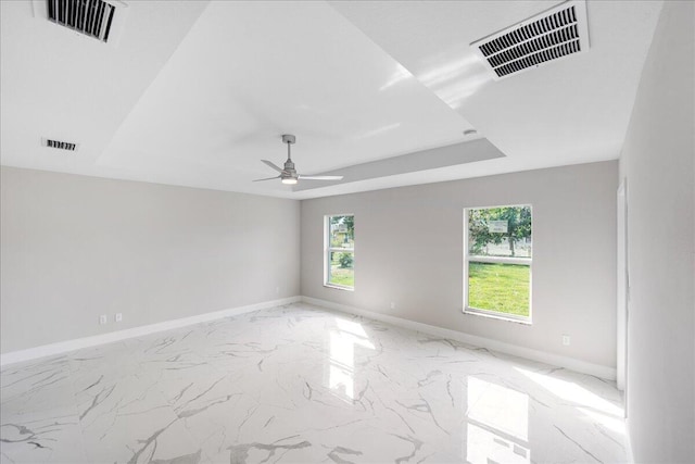 empty room with a raised ceiling and ceiling fan