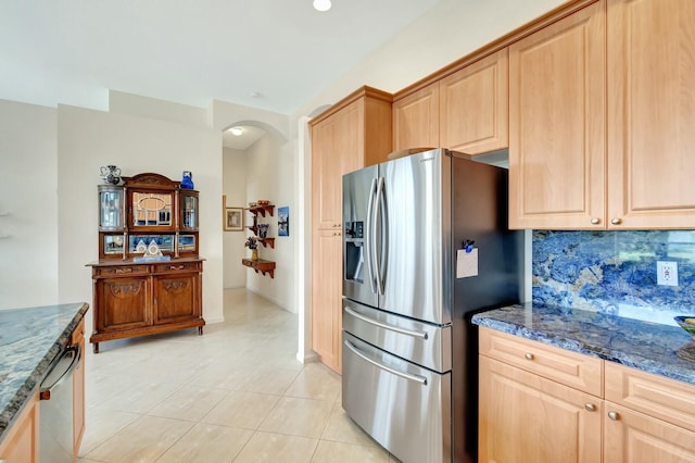 kitchen with dark stone countertops, arched walkways, stainless steel appliances, and backsplash