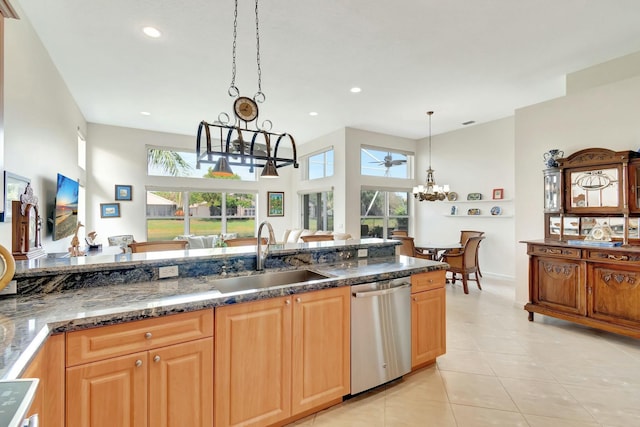 kitchen featuring dark stone counters, dishwasher, pendant lighting, a sink, and light tile patterned flooring