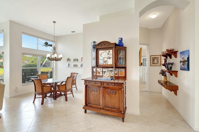 dining area featuring arched walkways, a chandelier, a towering ceiling, and baseboards