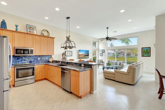 kitchen featuring stainless steel appliances, backsplash, open floor plan, a sink, and a peninsula